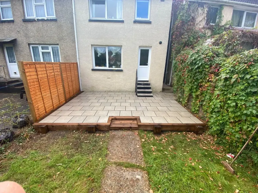 Garden after the work: raised grey porcelain patio with timber sleeper edging, fence screen and new steps