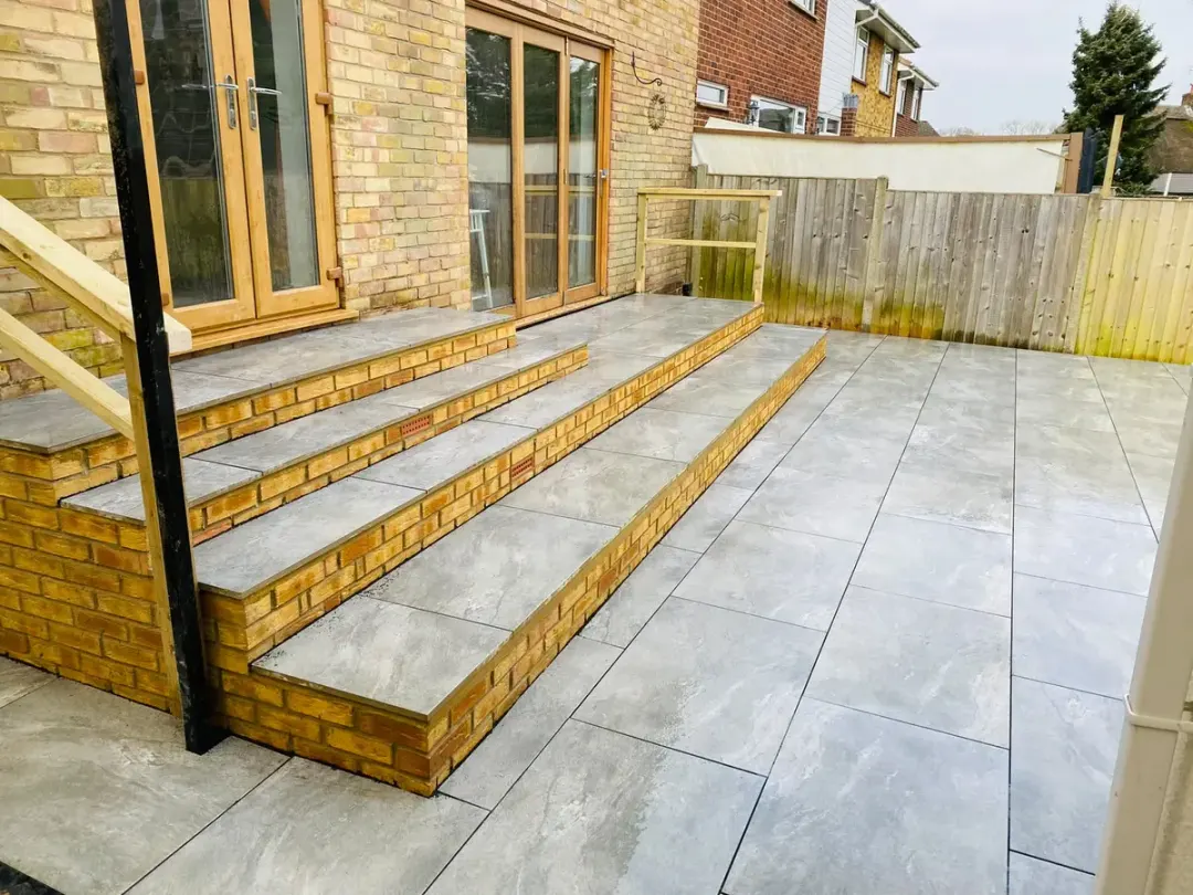 Wide brick steps with porcelain treads leading down to the patio