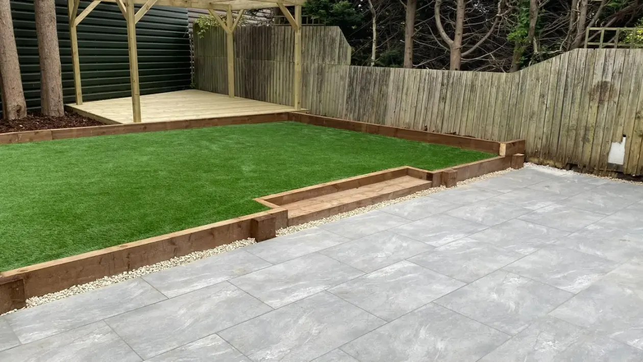 Artificial lawn with sleeper edging beside a grey porcelain patio