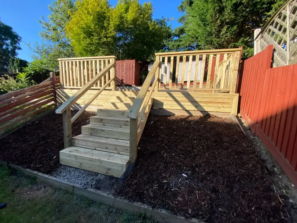 Raised timber deck with balustrade and stairs on a sloping garden