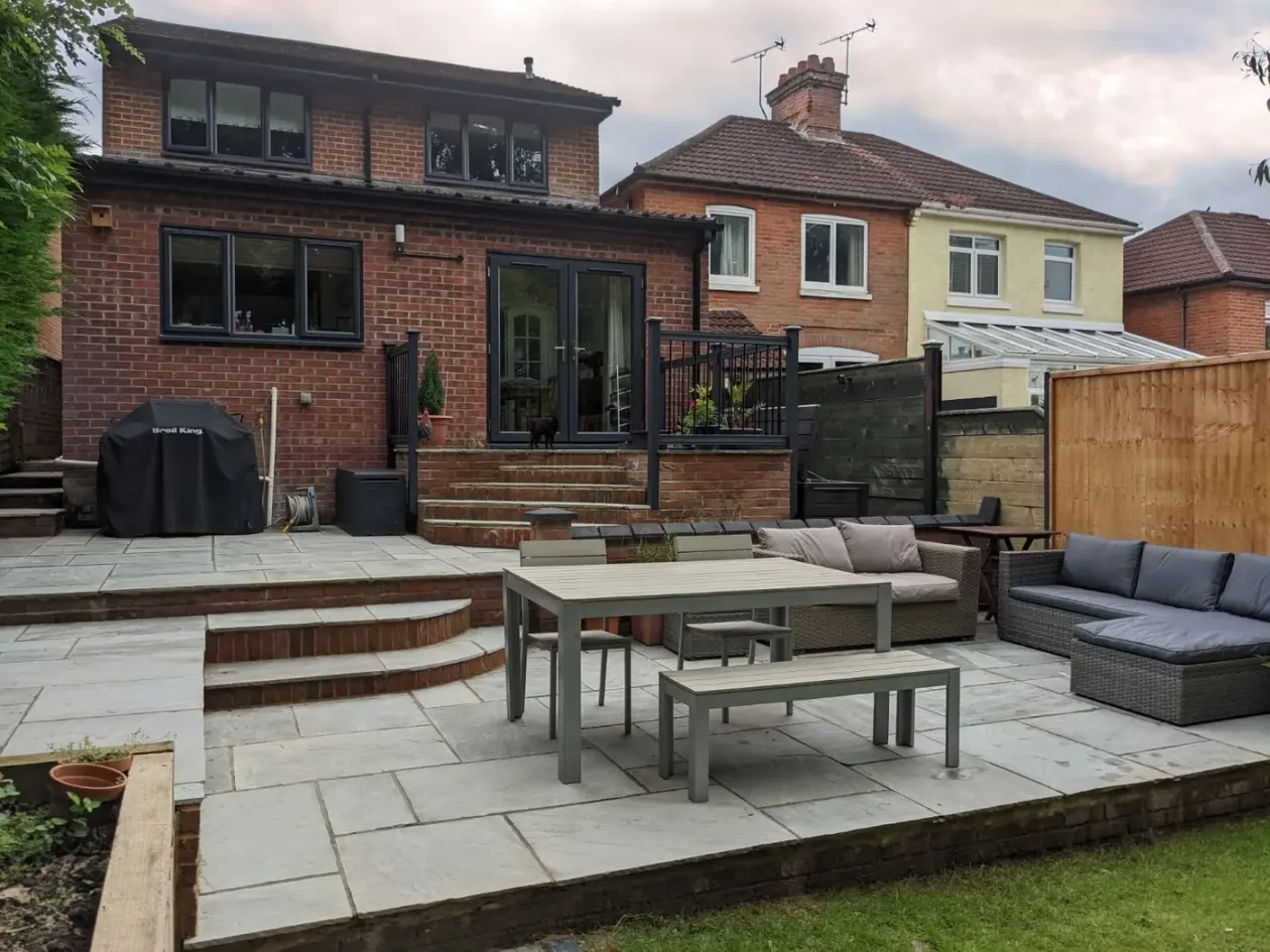 Split-level sandstone patio with brick steps, dining table and rattan seating